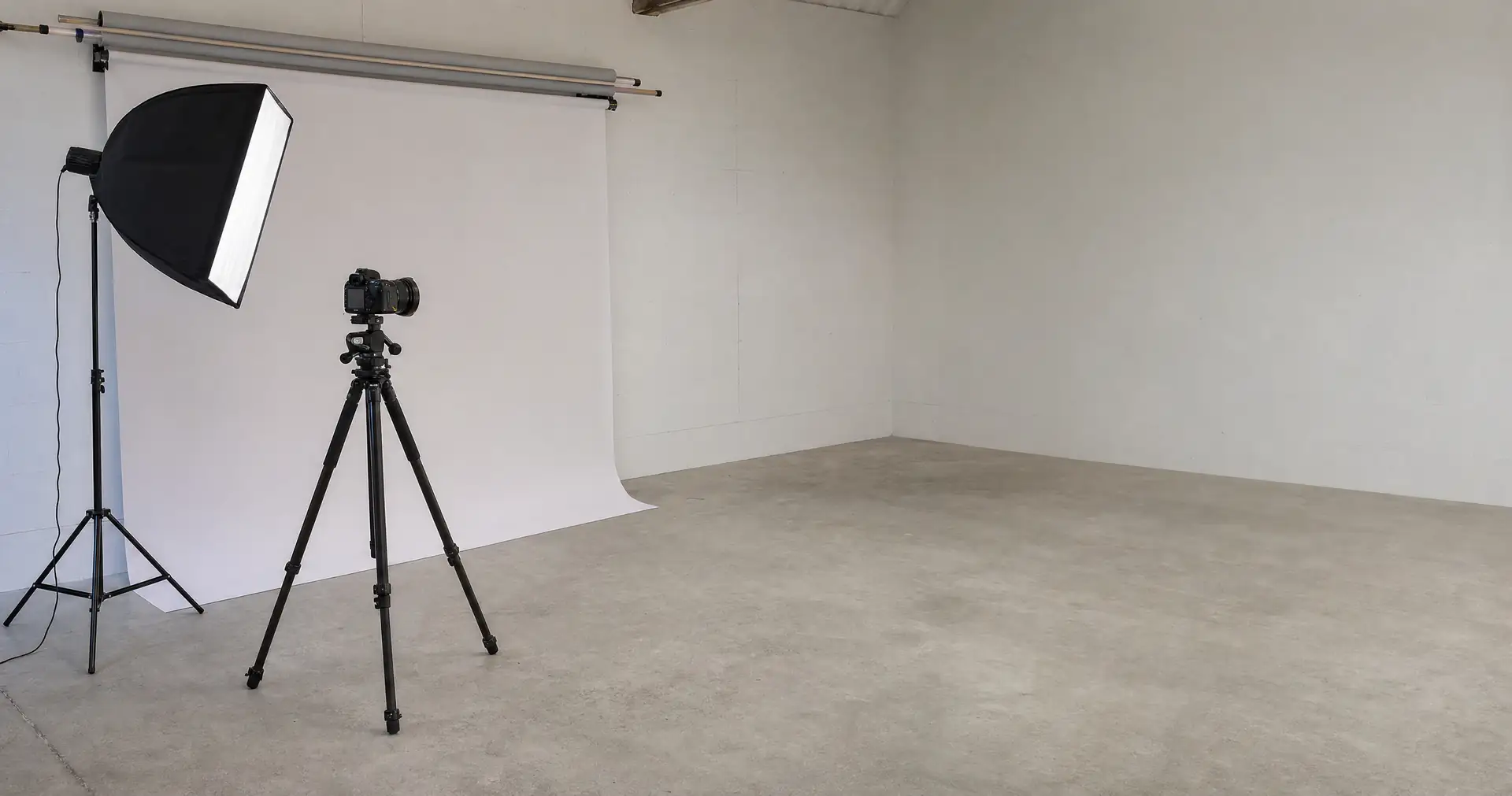 Lighting stands and a folded backdrop in an empty studio space